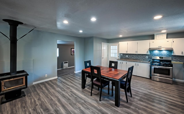 dining room with a wood stove, heating unit, a textured ceiling, and dark hardwood / wood-style floors