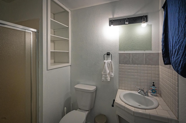 bathroom featuring toilet, a shower with shower door, vanity, built in features, and backsplash