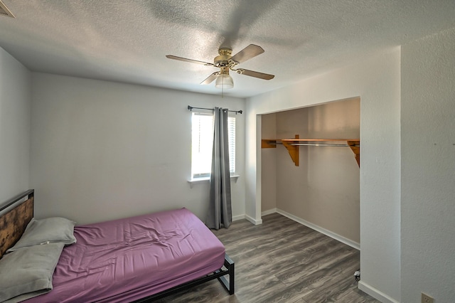 bedroom with dark wood-type flooring, a textured ceiling, ceiling fan, and a closet