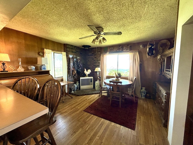 dining room with ceiling fan, dark hardwood / wood-style floors, and wooden walls