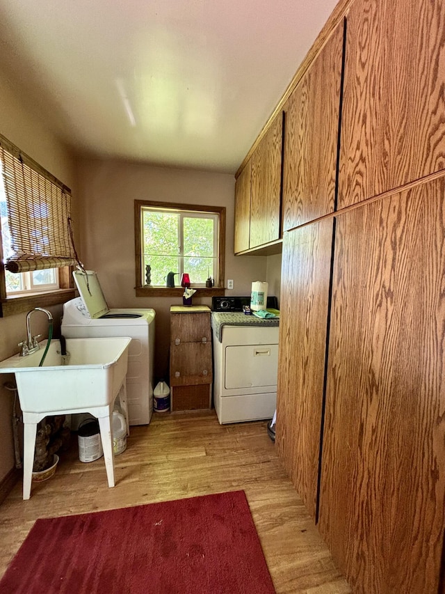 washroom featuring cabinets, washer and clothes dryer, and light wood-type flooring