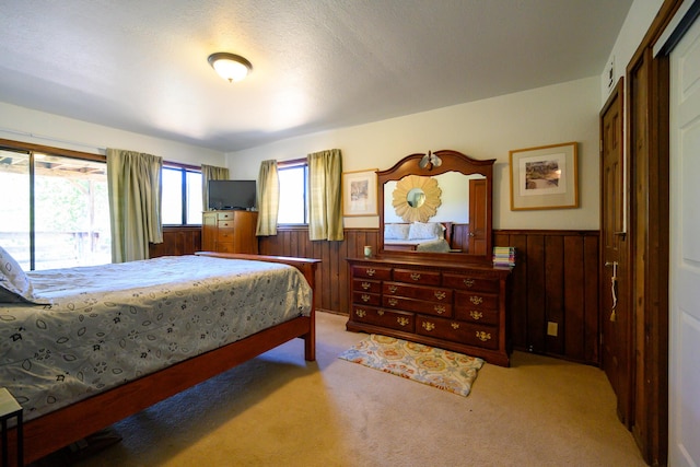 carpeted bedroom with wood walls and a textured ceiling