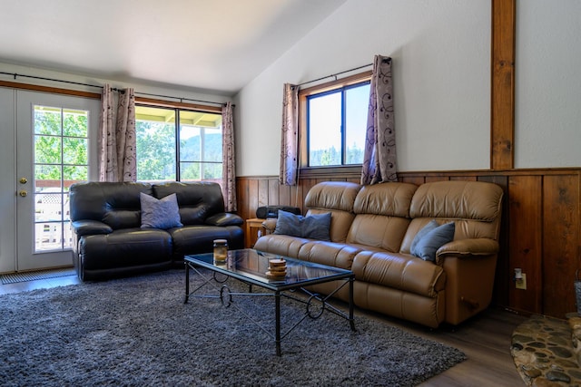 living room with wooden walls, a healthy amount of sunlight, lofted ceiling, and hardwood / wood-style flooring