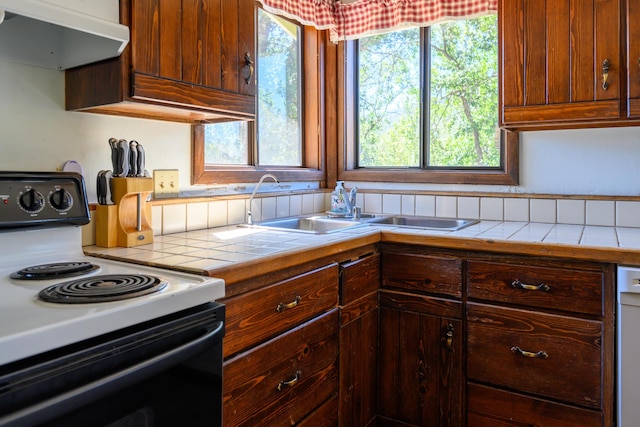 kitchen featuring white appliances, tile countertops, extractor fan, and a healthy amount of sunlight