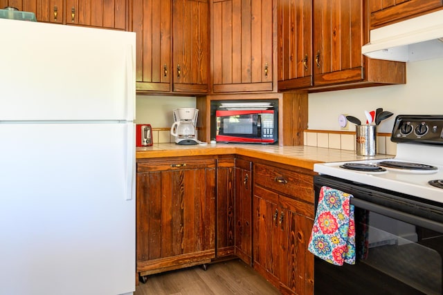 kitchen featuring wood-type flooring, white appliances, and tile counters