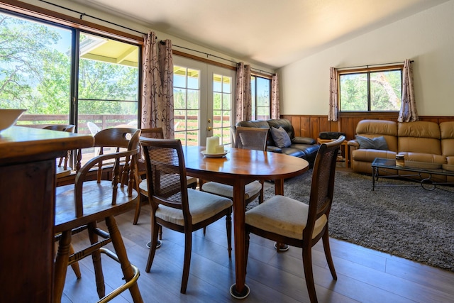 dining room featuring french doors, light hardwood / wood-style floors, lofted ceiling, and wood walls