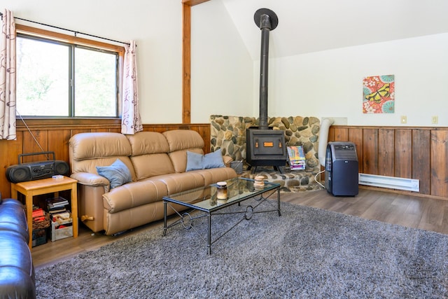 living room featuring vaulted ceiling, a wood stove, wooden walls, and dark hardwood / wood-style floors