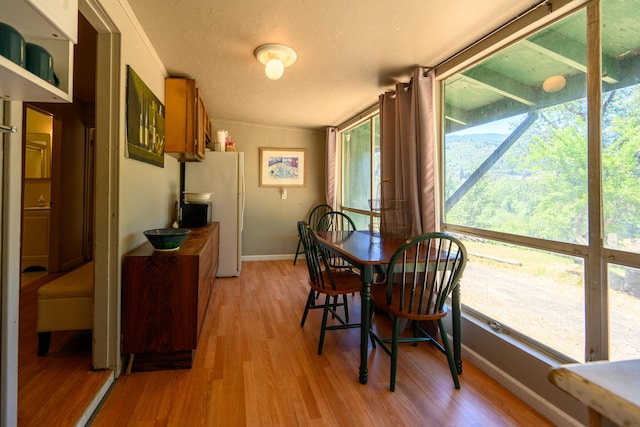 dining room featuring a textured ceiling, light hardwood / wood-style floors, and vaulted ceiling