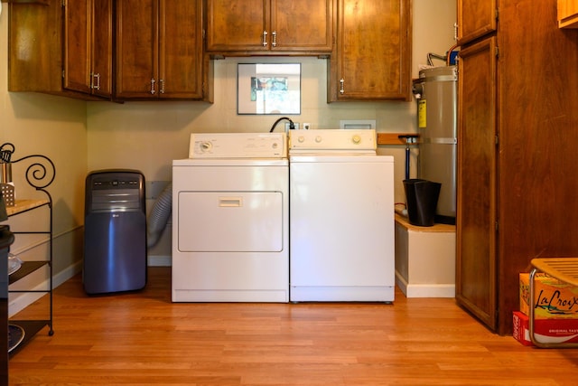 laundry room with cabinets, washing machine and dryer, gas water heater, and light hardwood / wood-style flooring