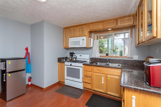 kitchen featuring hardwood / wood-style flooring, white appliances, sink, and a textured ceiling