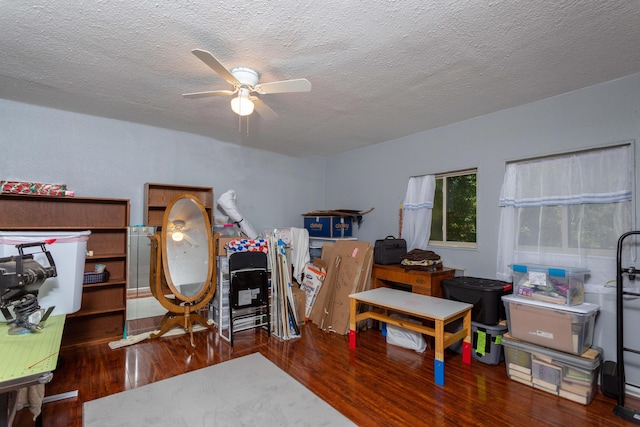 misc room featuring a textured ceiling, ceiling fan, and dark wood-type flooring