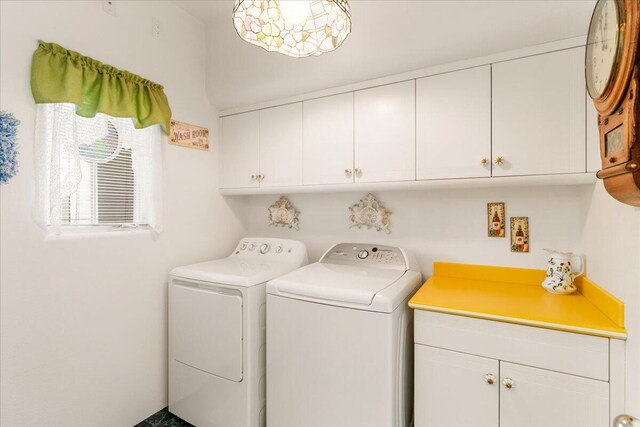 clothes washing area with cabinets and washing machine and clothes dryer