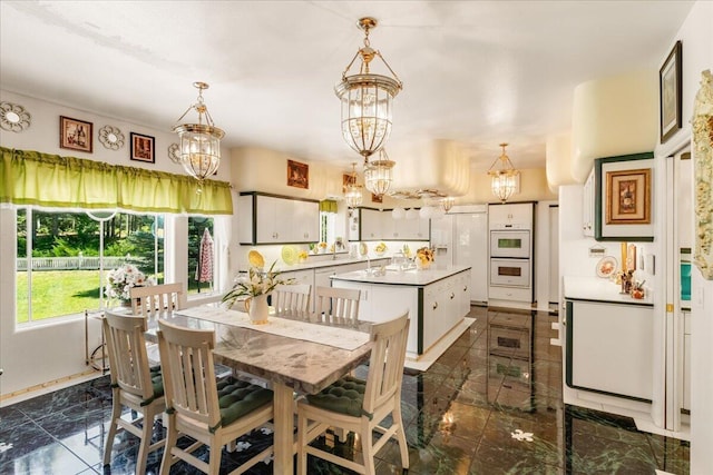 kitchen with a center island, white appliances, hanging light fixtures, and an inviting chandelier