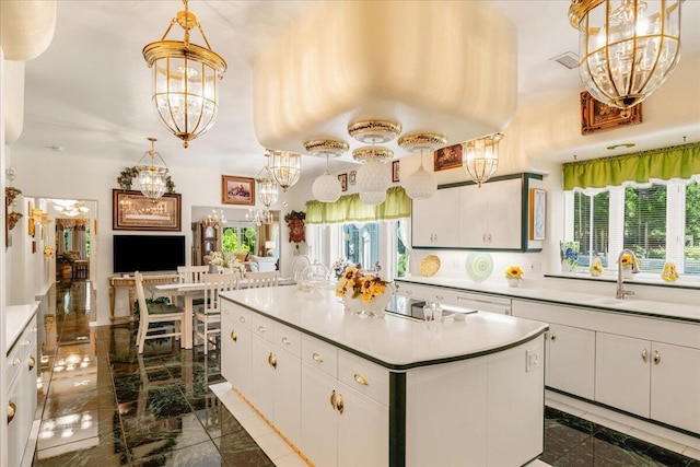 kitchen featuring white cabinetry, a kitchen island with sink, hanging light fixtures, and a healthy amount of sunlight