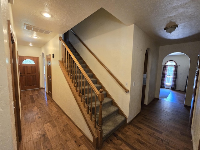 stairs with hardwood / wood-style flooring and a textured ceiling