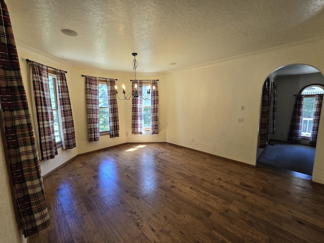 unfurnished dining area with a textured ceiling, a chandelier, crown molding, and dark hardwood / wood-style floors