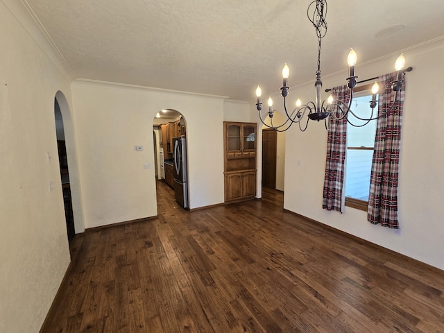 unfurnished dining area featuring dark hardwood / wood-style floors, ornamental molding, a textured ceiling, and an inviting chandelier