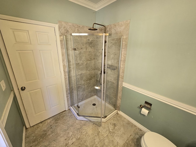 bathroom featuring ornamental molding, toilet, and a shower with shower door