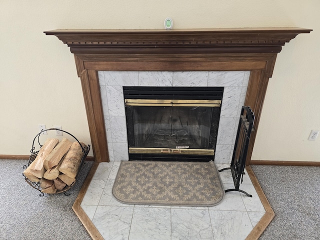 interior details with a tile fireplace and carpet flooring