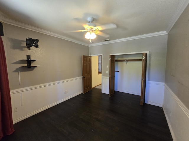 unfurnished bedroom featuring ceiling fan, dark hardwood / wood-style floors, ornamental molding, and a closet