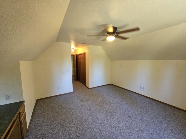 bonus room featuring a textured ceiling, carpet floors, vaulted ceiling, and ceiling fan