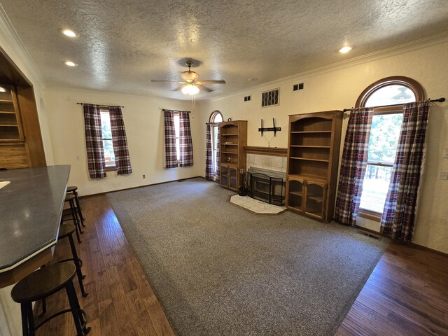 unfurnished living room featuring ceiling fan, dark hardwood / wood-style flooring, a healthy amount of sunlight, and a textured ceiling