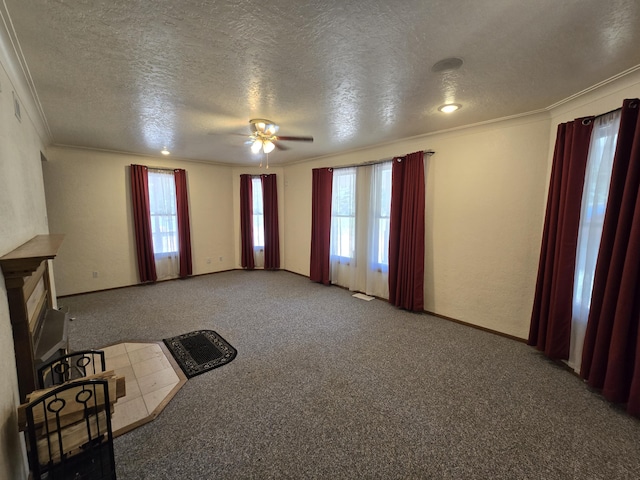 unfurnished living room featuring ceiling fan, ornamental molding, carpet floors, and a textured ceiling