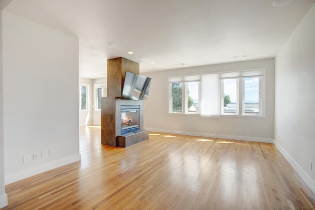 unfurnished living room featuring a fireplace, light hardwood / wood-style flooring, and a healthy amount of sunlight