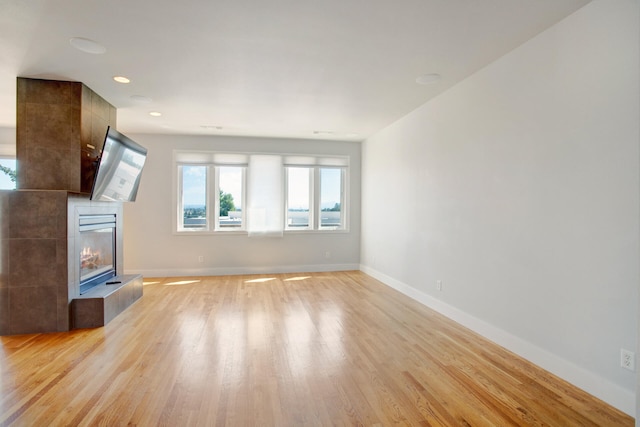 unfurnished living room with a tile fireplace and light wood-type flooring