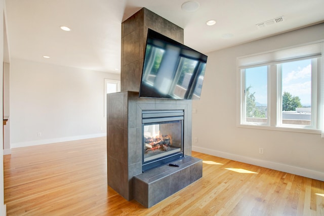 living room with a tiled fireplace and light hardwood / wood-style flooring