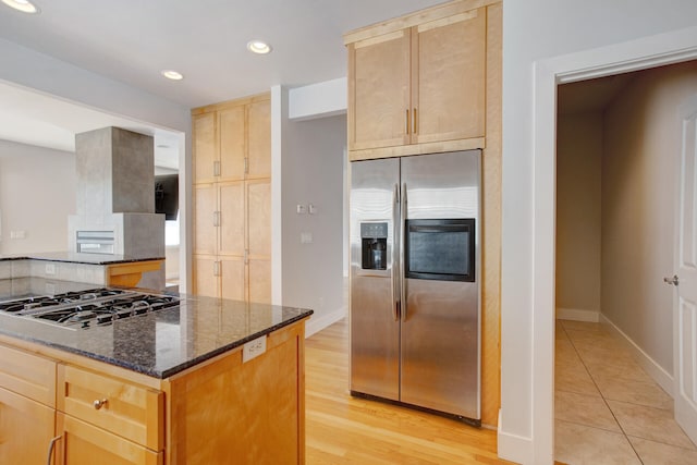 kitchen featuring light hardwood / wood-style floors, dark stone countertops, stainless steel appliances, and light brown cabinets