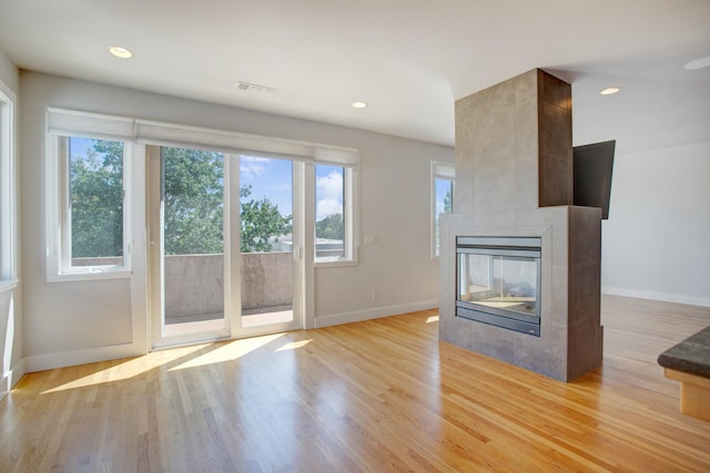 unfurnished living room featuring a tiled fireplace and light hardwood / wood-style floors