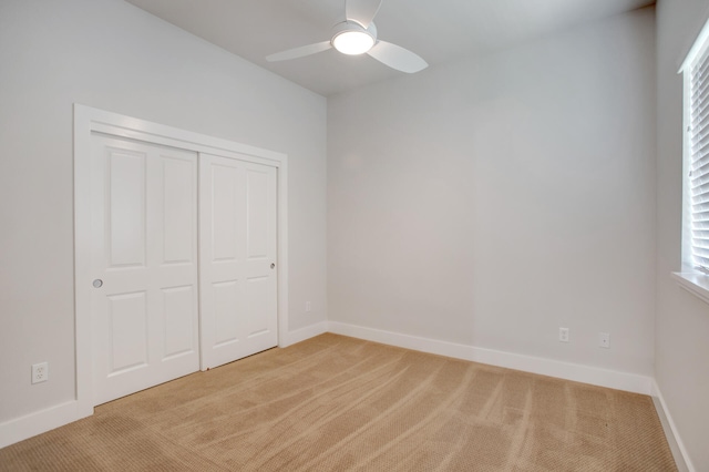 unfurnished bedroom with ceiling fan, light carpet, and a closet