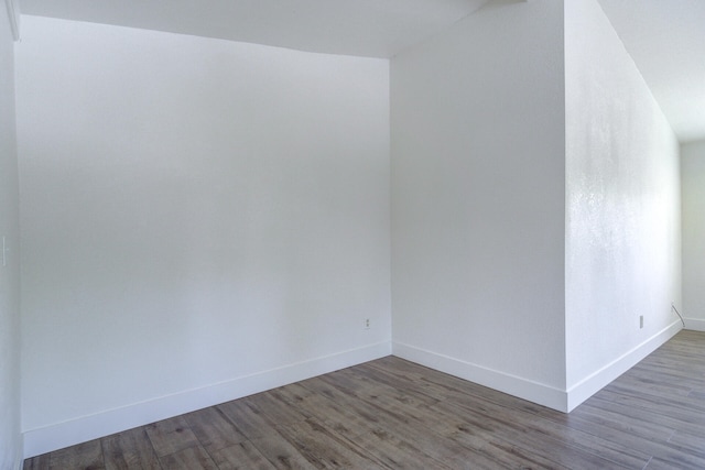 spare room featuring baseboards and wood finished floors