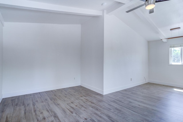 unfurnished room featuring baseboards, lofted ceiling with beams, a ceiling fan, and wood finished floors