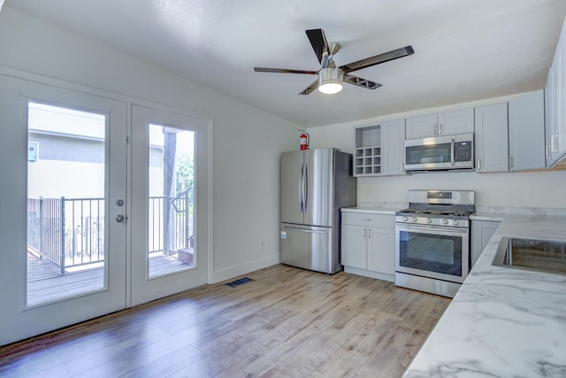 kitchen with appliances with stainless steel finishes, light stone counters, french doors, light wood-style flooring, and visible vents