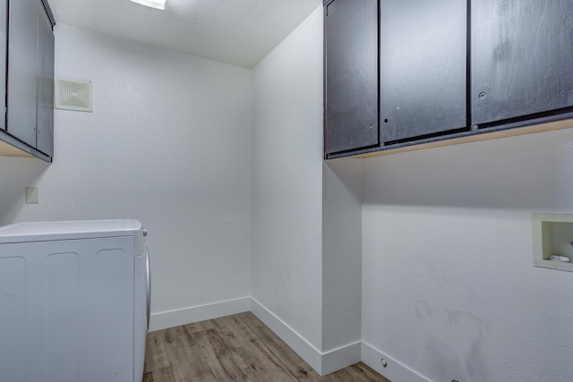 laundry area featuring baseboards, light wood-style flooring, cabinet space, and washer / clothes dryer