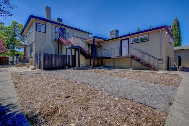 rear view of house with fence, a chimney, and stairs