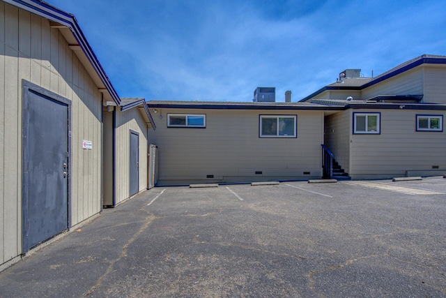 back of property featuring central AC unit, uncovered parking, and crawl space