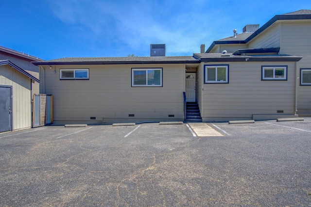 back of property featuring entry steps, uncovered parking, and crawl space