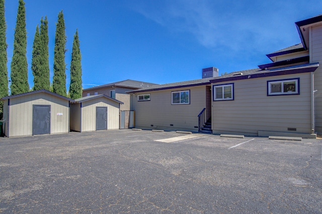 back of property featuring an outdoor structure, a chimney, a shed, and crawl space