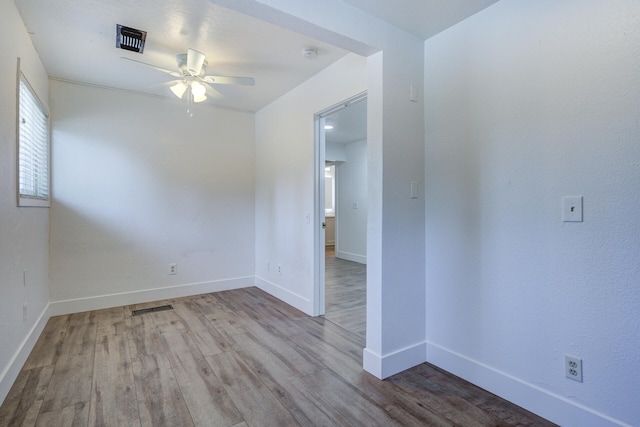 spare room with baseboards, ceiling fan, wood finished floors, and visible vents