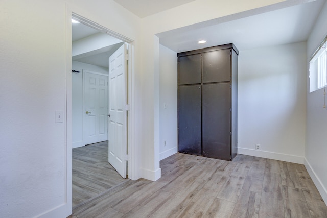 unfurnished bedroom with light wood-style floors, baseboards, and a closet