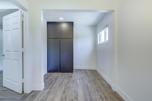 unfurnished bedroom with baseboards, light wood-style flooring, and a closet