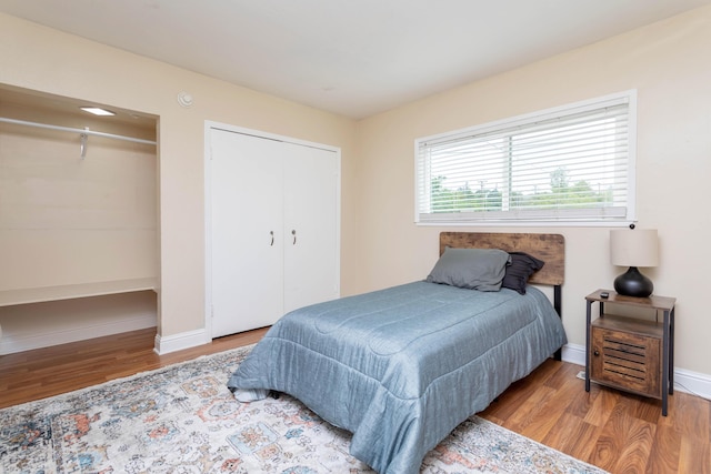 bedroom featuring baseboards, wood finished floors, and a closet