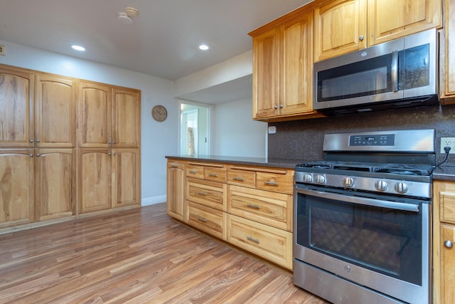 kitchen featuring decorative backsplash, dark countertops, light wood-style floors, recessed lighting, and stainless steel appliances
