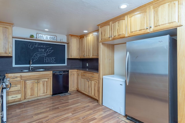 kitchen featuring dark countertops, appliances with stainless steel finishes, a sink, light wood-style floors, and recessed lighting