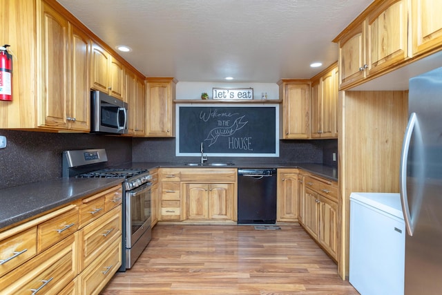 kitchen with a sink, backsplash, dark countertops, and stainless steel appliances
