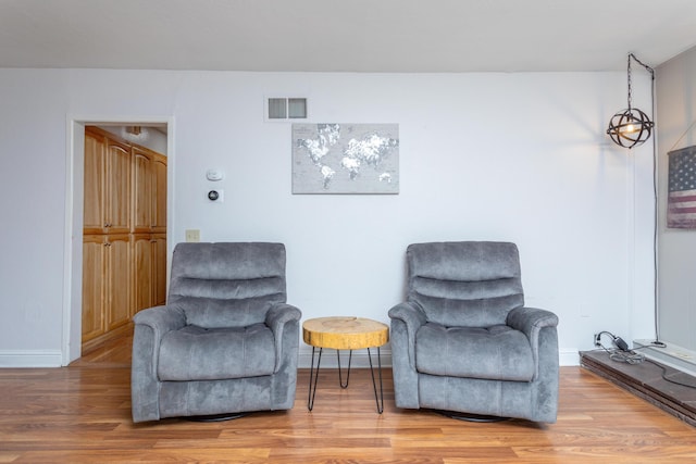sitting room featuring baseboards, visible vents, and light wood finished floors