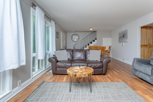 living area with stairs, baseboards, visible vents, and light wood-type flooring